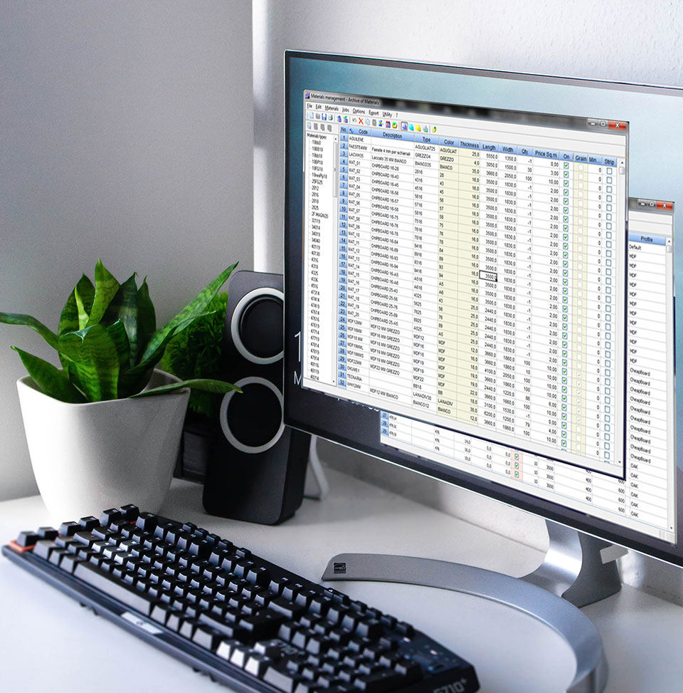 Egy fehér irodai fülkében egy fehér asztalon egy monitor, és egy billentyűzet látható, a monitoron egy adattáblázattal.