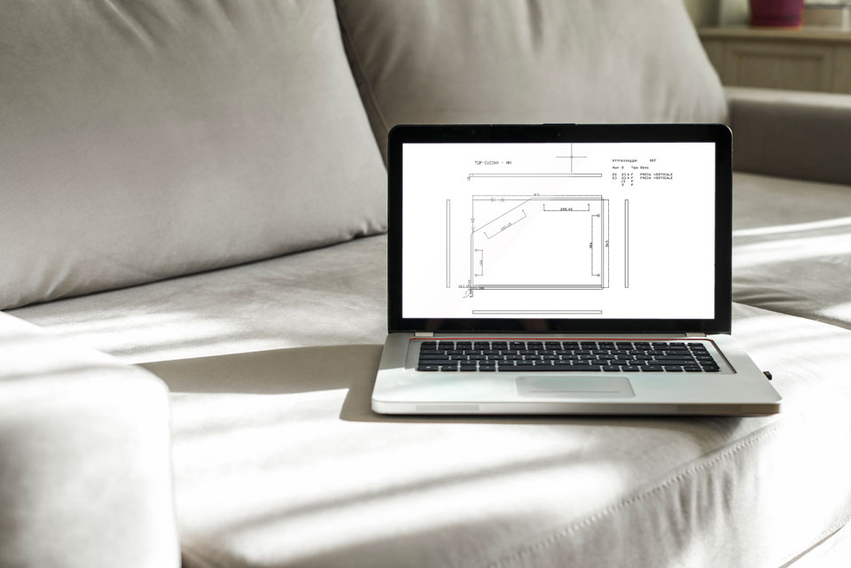 Egy otthoni irodában a kanapén egy laptop, rajta egy tábla és a méretezése látható.