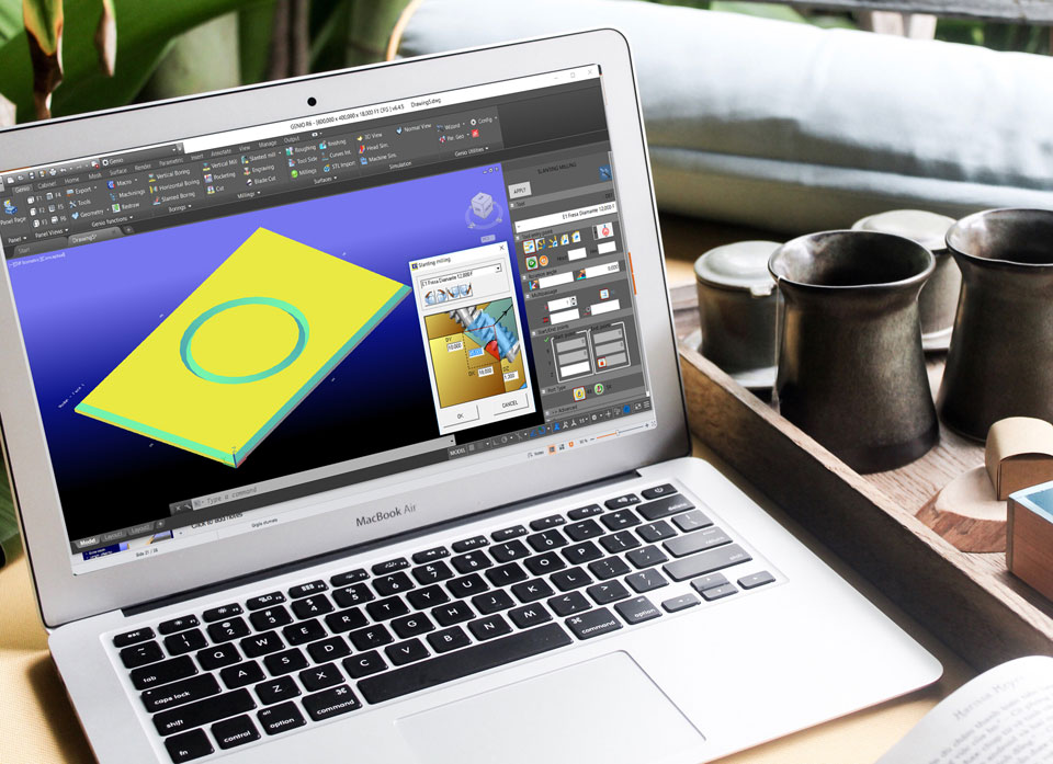 Egy fa tálca mellett egy laptopon 3D CAD alkalmazás látható, amin egy munkadarab szélei kb. 45 fokban le vannak marva, illetve a tetején, középpen egy gyűrű alakú bemarással.