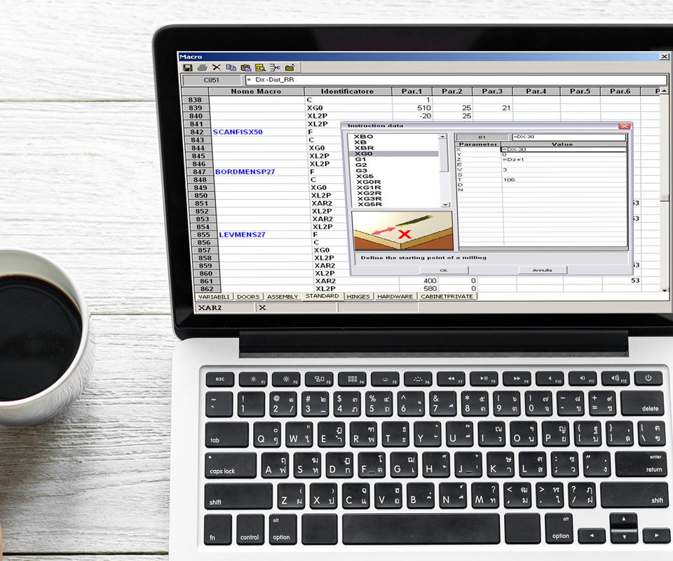 Fehér fa asztalon egy bögre kávé és egy laptop, amin adattáblázat látható.