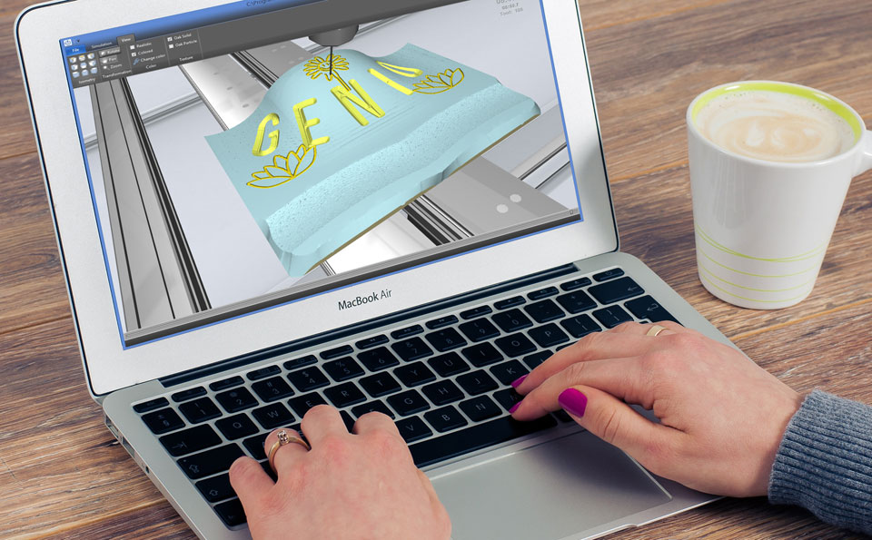 Egy laptopon CAD-es felületen egy 3D-s, hajlított felületű munkadarabba marnak egy Genio logót és különböző mintákat.